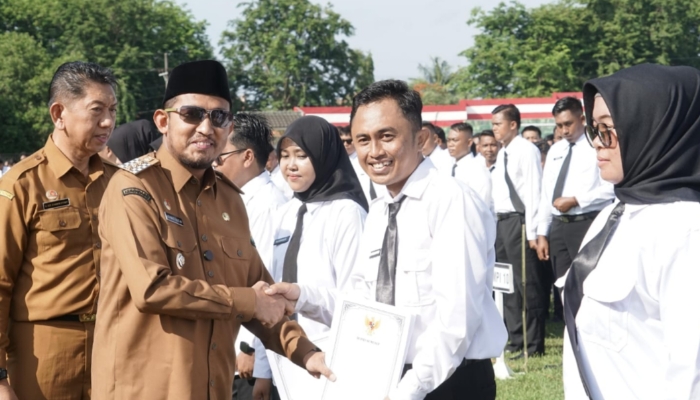 SEREMONI. Bupati Sumenep Achmad Fauzi Wongsojudo, menyerahkan SK kepada salah satu penerima formasi PPPK Paruh Waktu dalam apel penyerahan resmi yang digelar di Stadion GOR A. Yani Pangligur, Senin (1/12/2025)