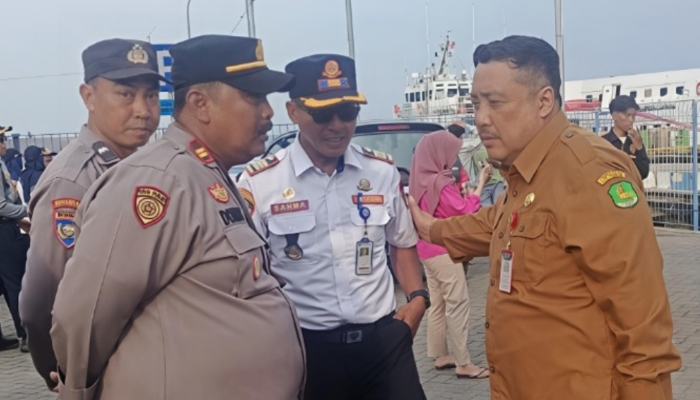 KOMUNIKASI. Plt Kepala Disperkimhub Sumenep Achmad Dzulkarnain (kiri), berbincang dengan aparat keamanan saat memantau langsung pemberangkatan program Mudik Gratis “Bismillah Melayani” di Pelabuhan Kalianget. (Istimewa for MaduraPost)