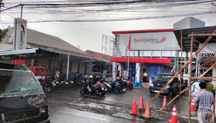 DIRENOVASI. Suasana di depan kantor Bank Jatim Cabang Sumenep saat hujan, lokasi yang tengah menjadi perhatian publik terkait dugaan fraud Rp23 miliar. (M.Hendra.E/MaduraPost)