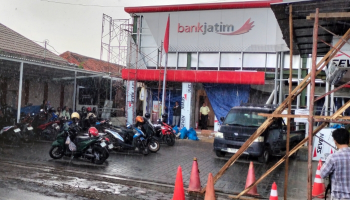 DIRENOVASI. Suasana di depan kantor Bank Jatim Cabang Sumenep saat hujan, lokasi yang tengah menjadi perhatian publik terkait dugaan fraud Rp23 miliar. (M.Hendra.E/MaduraPost)