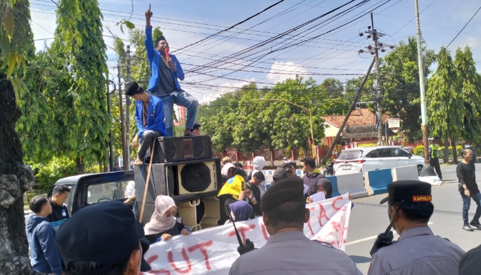 UNJUK RASA. Keterangan Foto: Sejumlah mahasiswa PMII Komisariat UNIJA menyampaikan orasi di atas mobil komando saat menggelar aksi unjuk rasa di depan Kantor BRI Cabang Sumenep, dikawal aparat kepolisian. (Istimewa for MaduraPost)